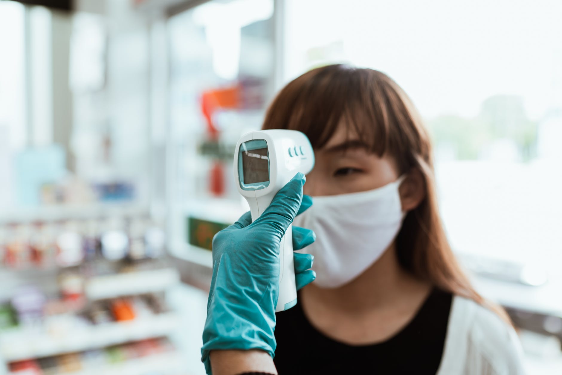 woman wearing a face mask getting her temperature checked